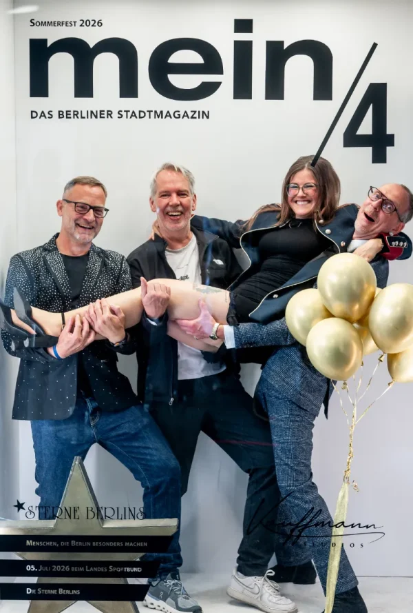 Vor einer Fotowand mit der Aufschrift „mein/4