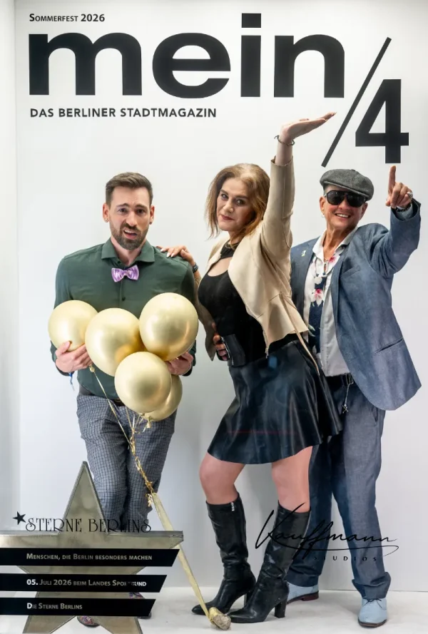 Vor einer Fotowand mit der Aufschrift „mein/4