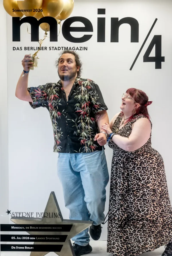 Vor einer Fotowand mit der Aufschrift „mein/4