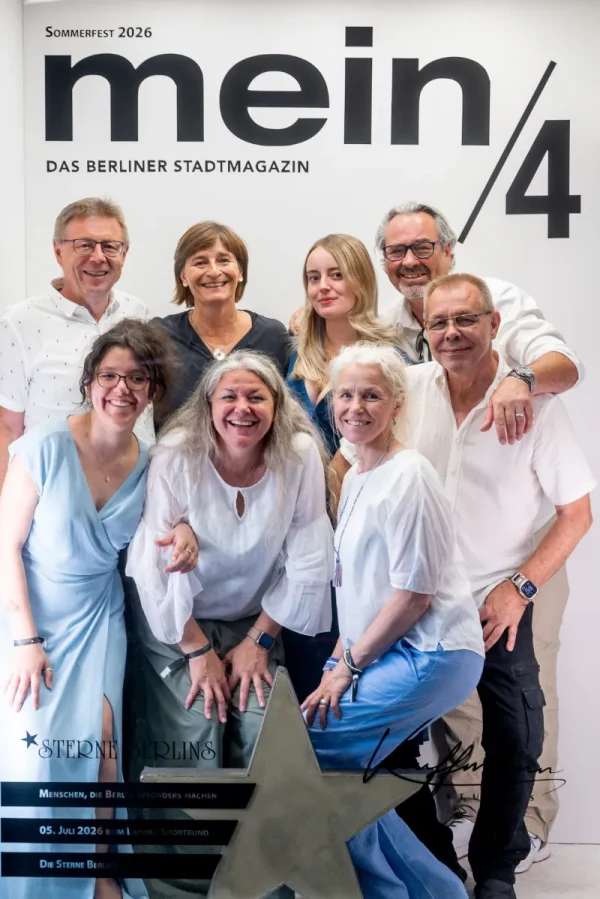 Vor einer Fotowand mit der Aufschrift „mein/4