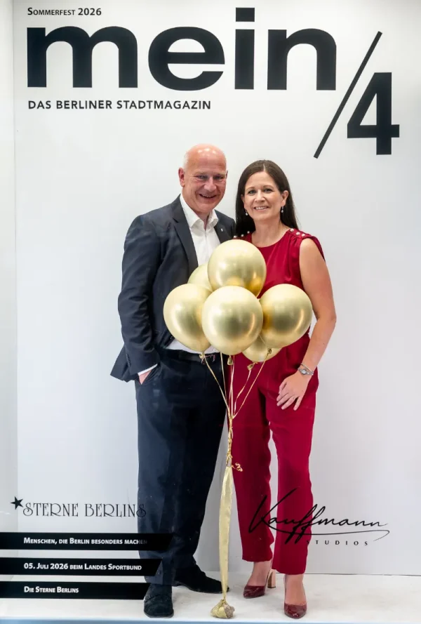 Vor einer Fotowand mit der Aufschrift „mein/4