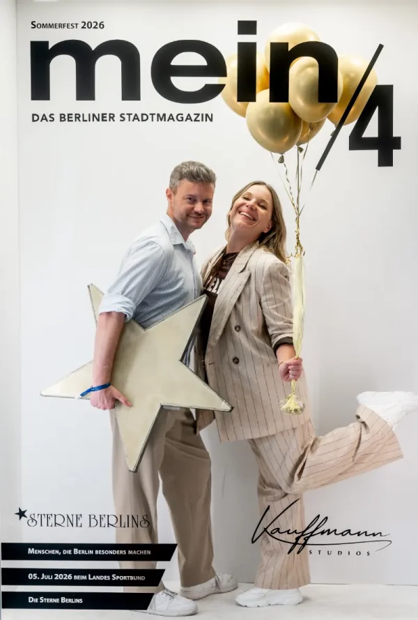 Fotobox-Aufnahme: Paar posiert fröhlich mit goldenem Stern und Luftballons vor der Sommerfest-Wand