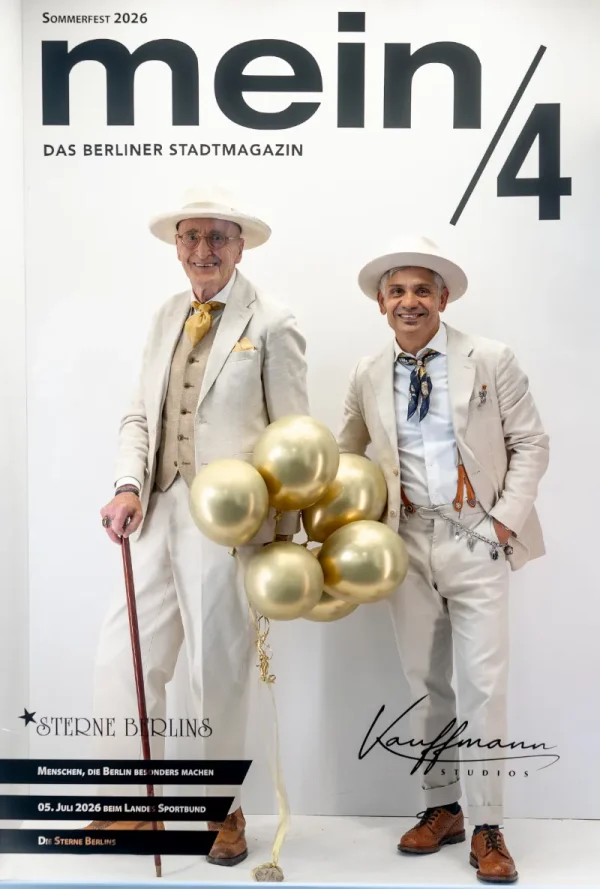 Vor einer Fotowand mit der Aufschrift „mein/4