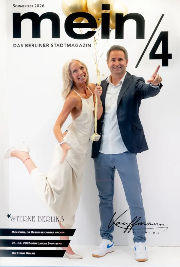 Vor einer Fotowand mit der Aufschrift „mein/4