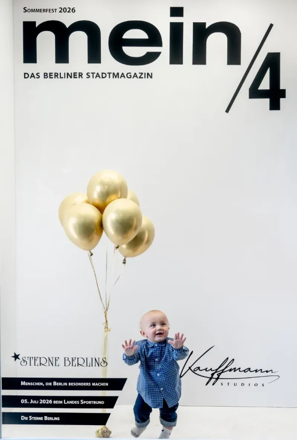 Vor einer Fotowand mit der Aufschrift „mein/4