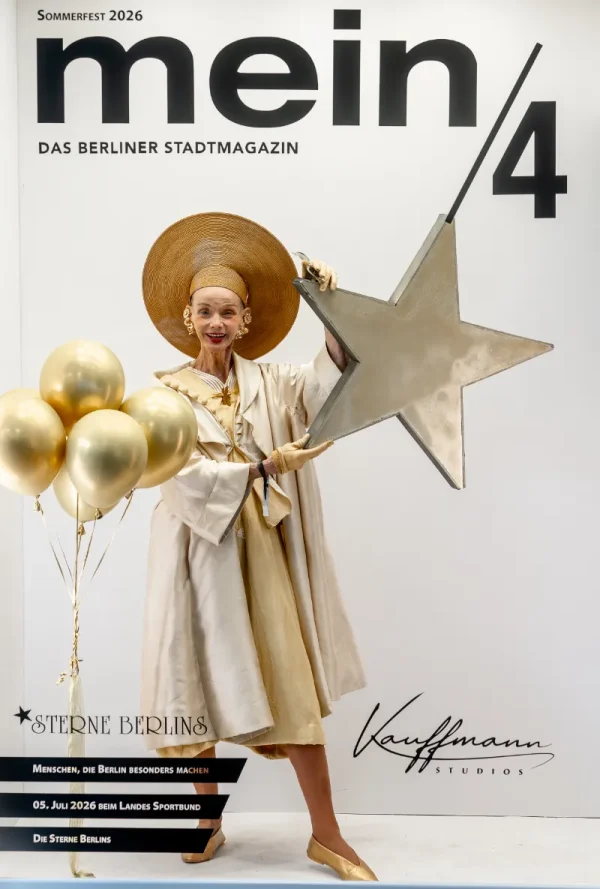 Vor einer Fotowand mit der Aufschrift „mein/4
