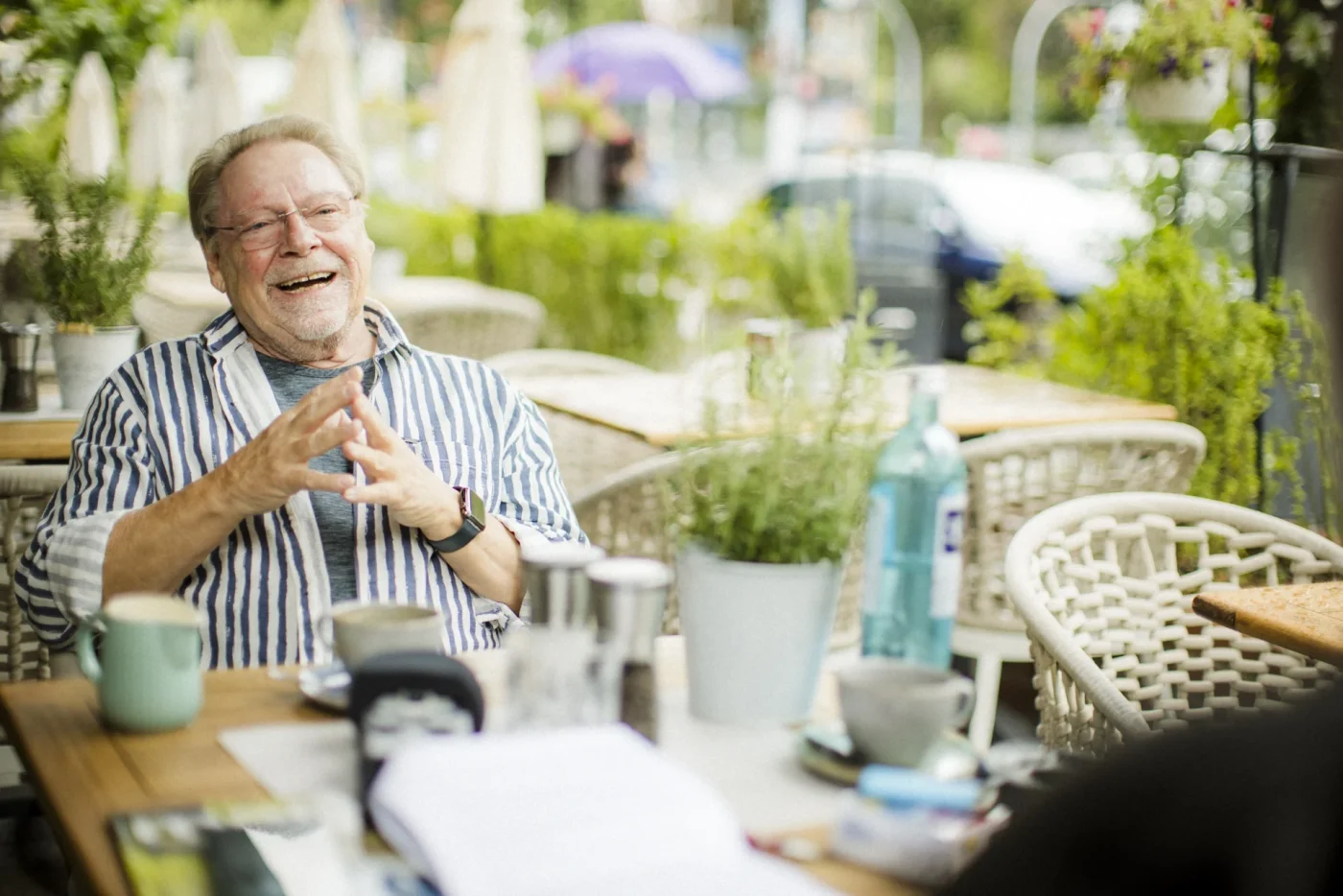 Jürgen von der Lippe sitzt lachend in einem Straßencafé