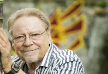 Jürgen von der Lippe lehnt lächelnd an einer Ziegelmauer